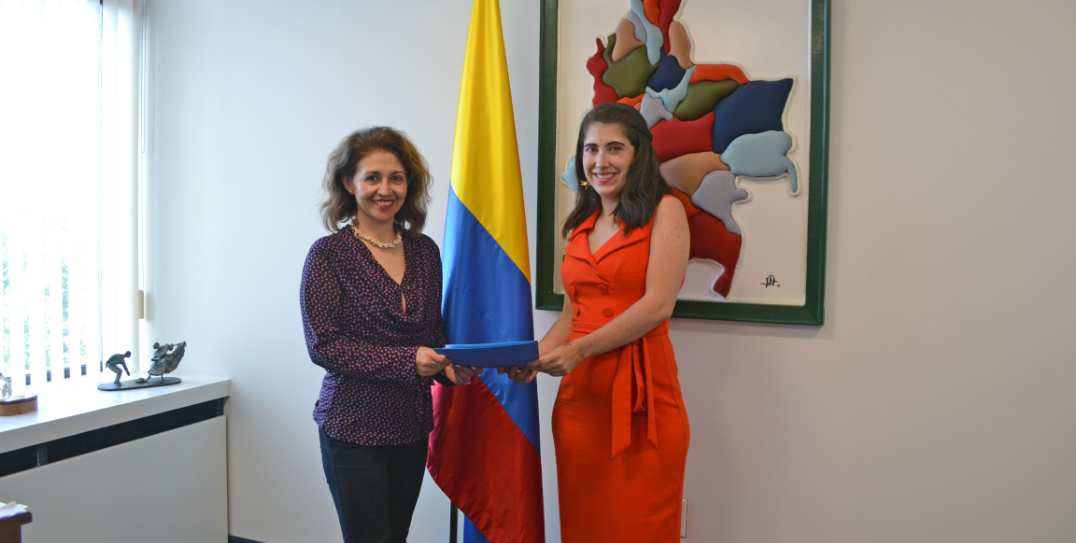 two women standing in front of a colombian flag